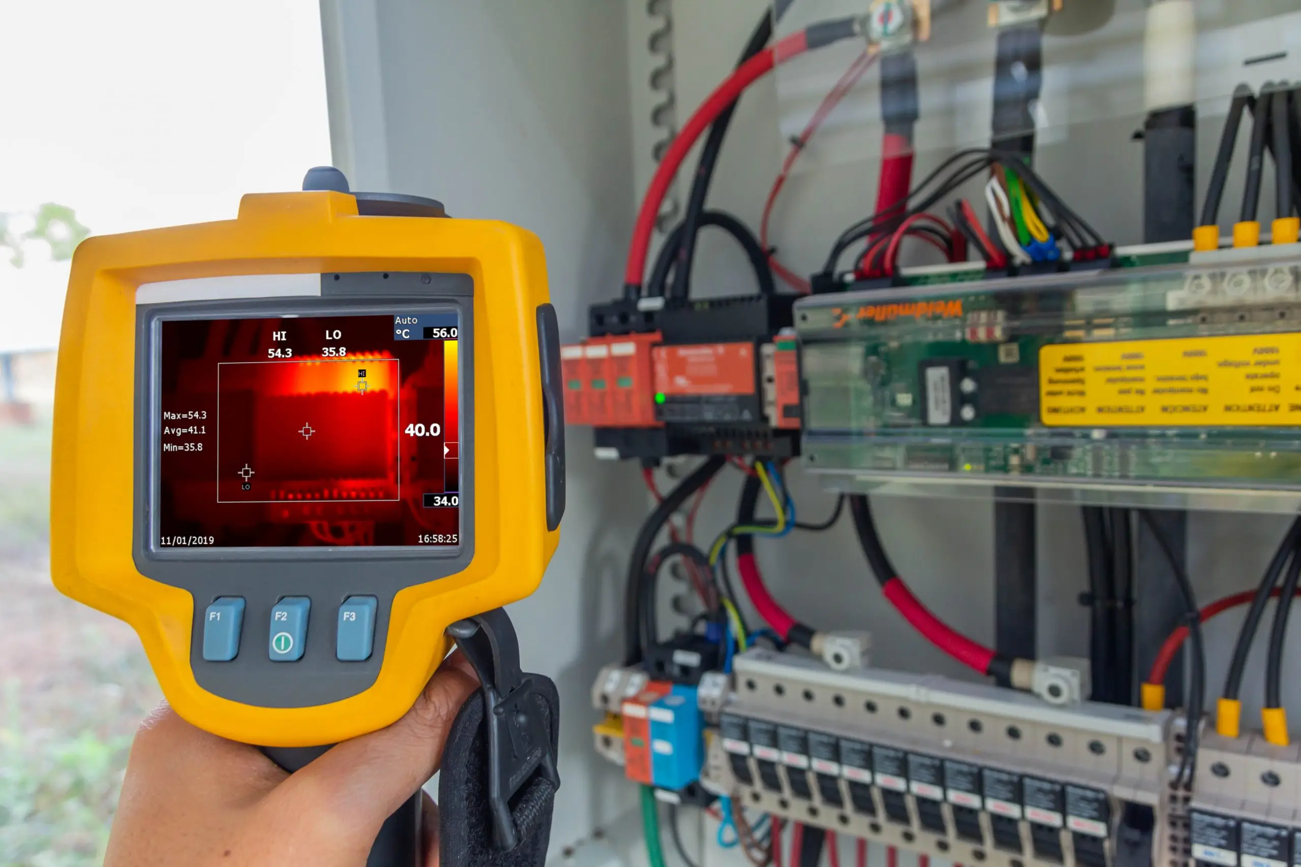 Termografisk kamera rettet mot et elektrisk anlegg, med varmebilde i displayet